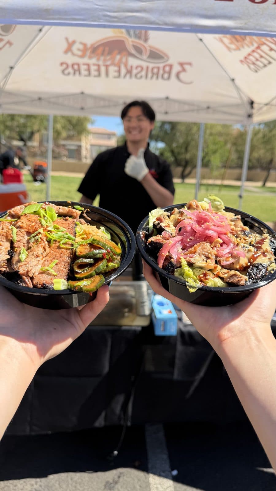 Two Brisketeer Bowls held up at the 3 Brisketeers Annex tent