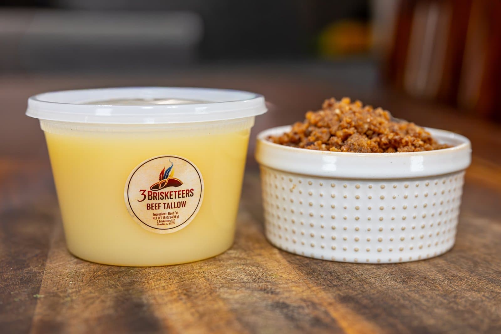 A tub of 3 Brisketeers beef tallow next to a ramekin of beef cracklin'